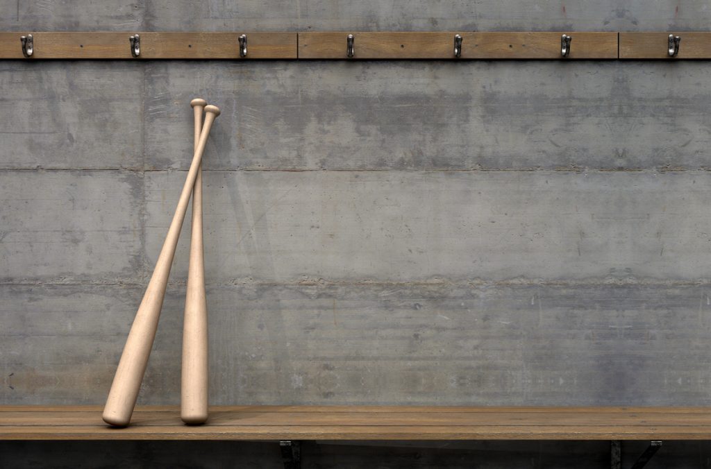 Wooden baseball bats leaning against a wall in a locker room