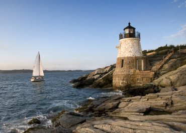 New England shoreline with a sailboat and lighthouse