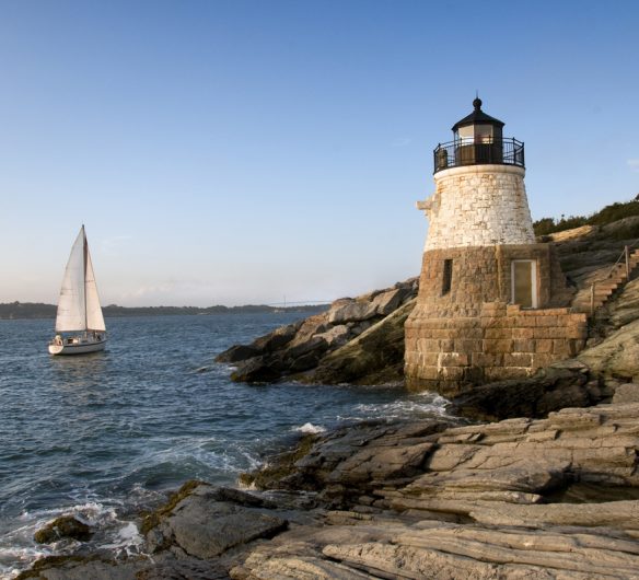 New England shoreline with a sailboat and lighthouse