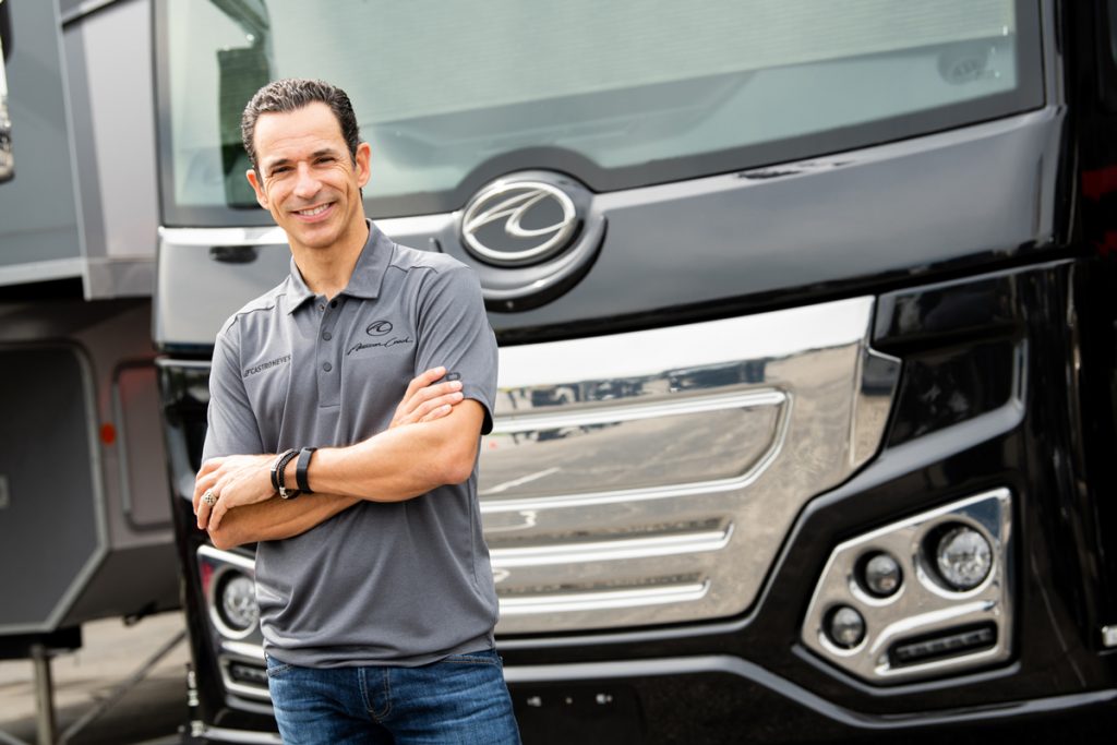 Helio Castroneves standing next to his RV 