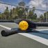 Pickleball and paddles laying on a court in front of a net on a sunny day.
