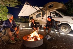 Friends sitting around a fire next to their RV