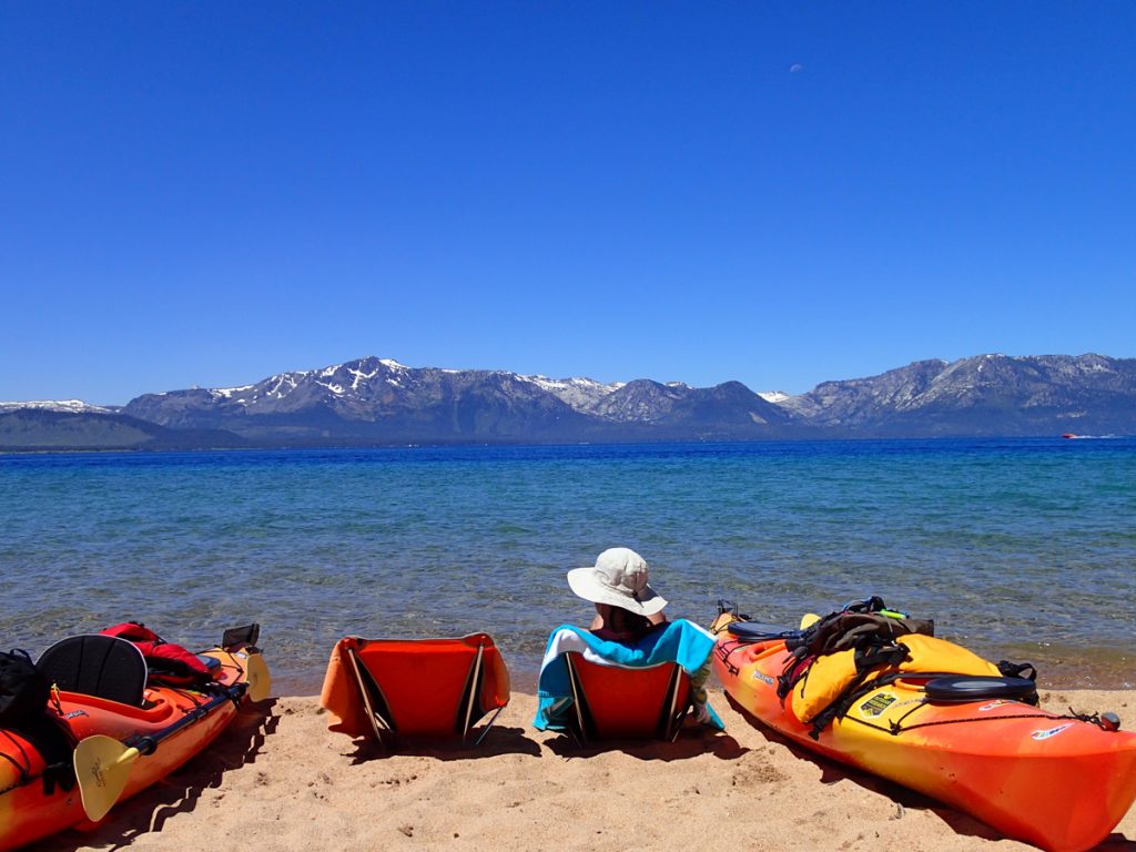 Tahoe Valley Campground - women sitting in a beach chair next to her kayak on the beach. 