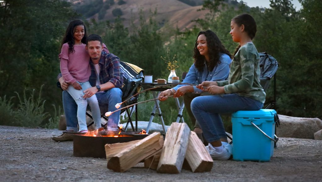 Family around a campfire roasting marshmallows 
